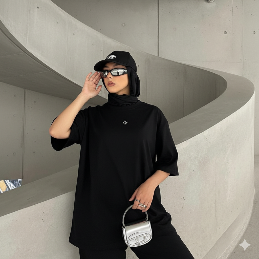 Une femme portant un t-shirt noir à manches courtes, un pantalon noir et un hijab noir.
