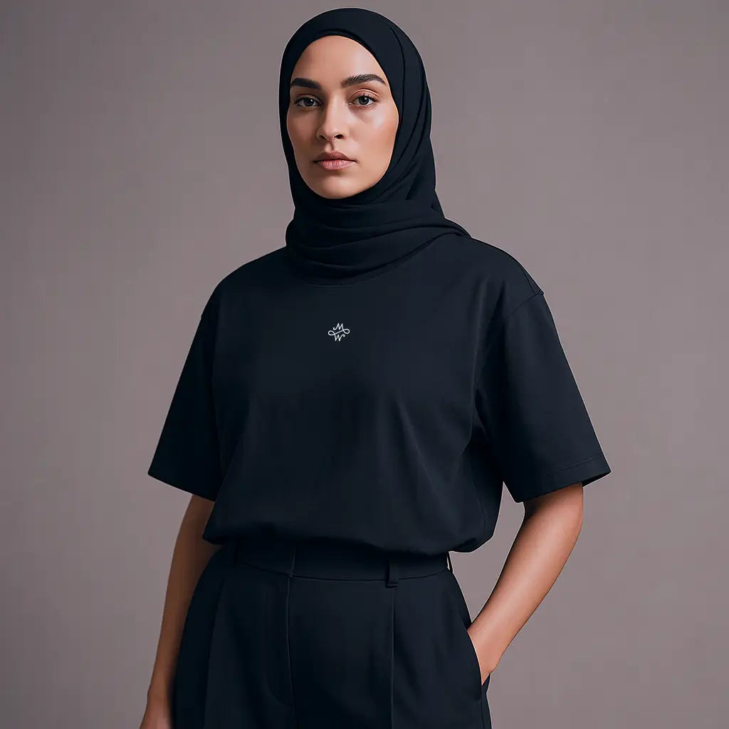 Une femme portant un t-shirt noir à manches courtes, un pantalon noir et un hijab noir.