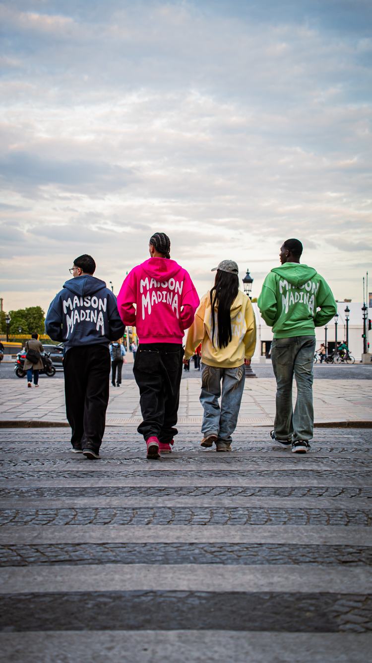 Quatre amis en hoodies Maison Madina traversent une place parisienne
